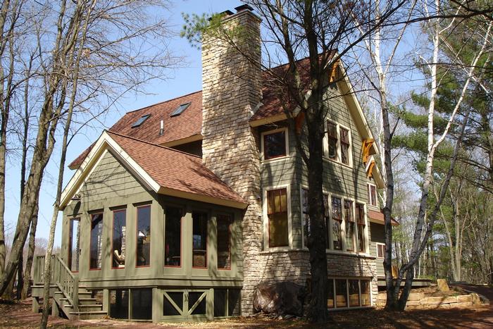 A large house with a red roof is surrounded by trees