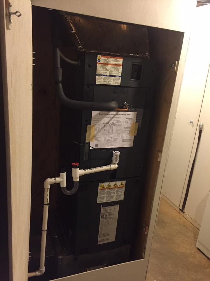 Open utility panel with pipes, valves, and labels inside a wall cavity