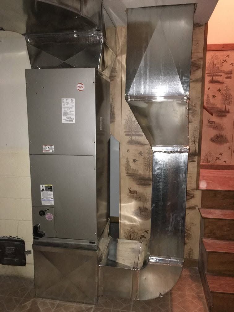 HVAC ductwork and furnace unit in a basement utility area with exposed pipes and insulation