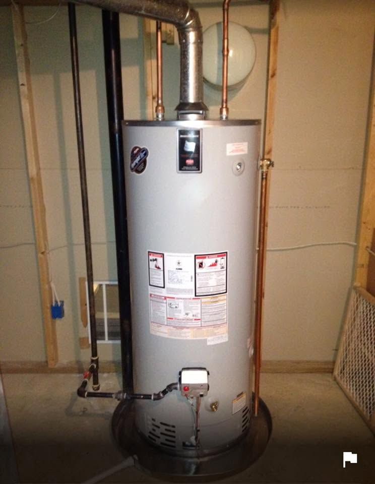 Gray water heater in a utility room with visible pipes and warning labels.