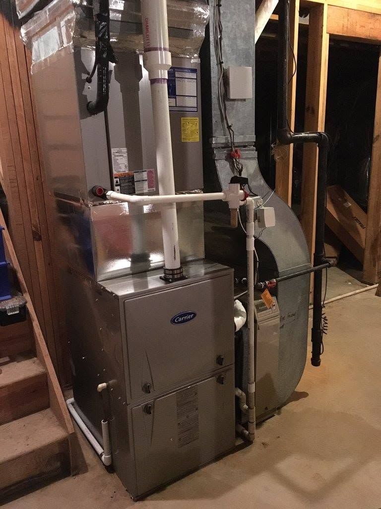 Furnace and HVAC ductwork in a basement utility area with metal pipes and an air handler.