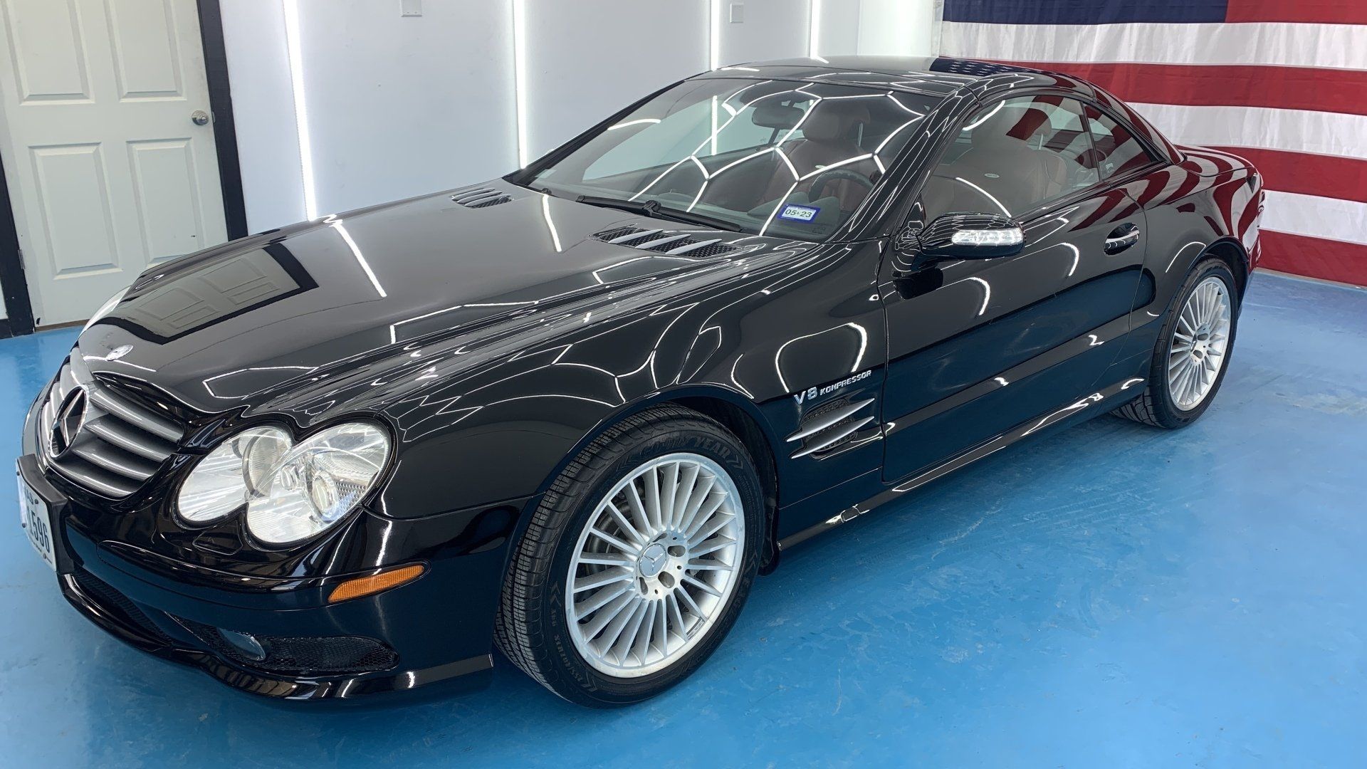 A black mercedes slr is parked in front of an american flag.