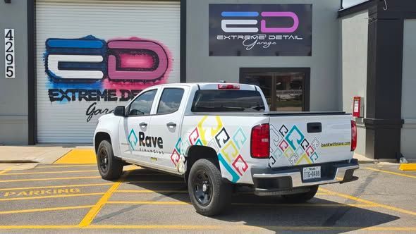 White pickup truck with colorful graphics parked outside an Extreme D garage