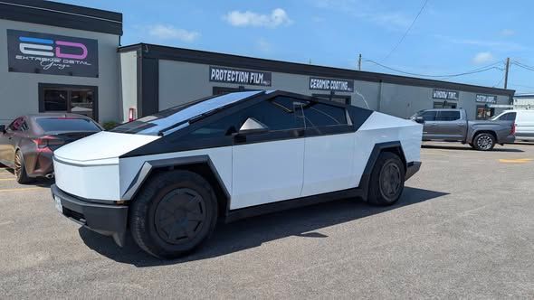 White Tesla Cybertruck parked outside a storefront on a sunny day