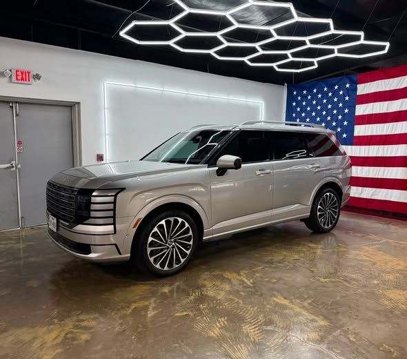 Silver SUV in a showroom with a large American flag on the wall and geometric ceiling lights.