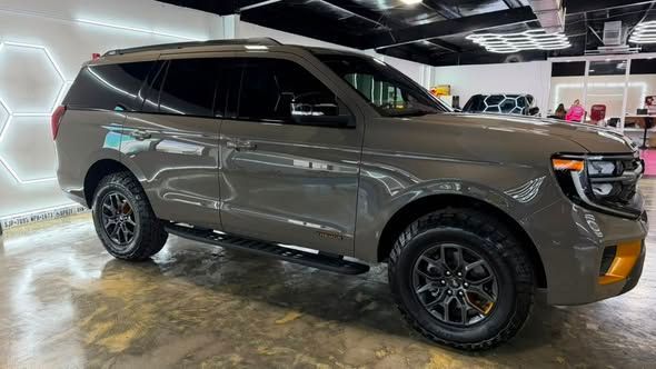 Brown SUV displayed indoors in a showroom, side view with black rims and chrome trim