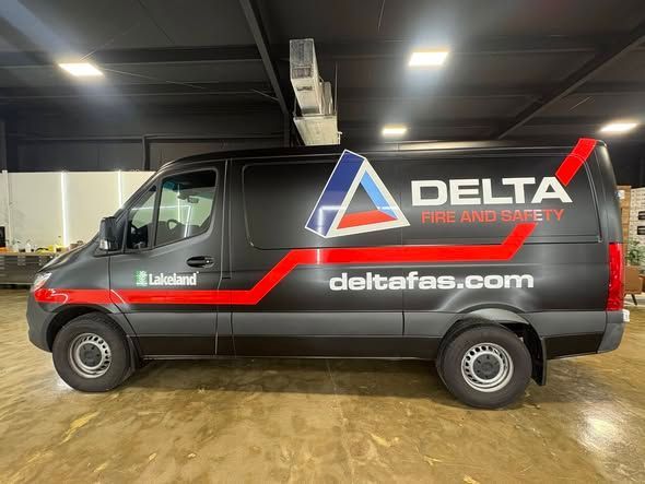 Black Delta Pest Management van with red logo and website parked indoors