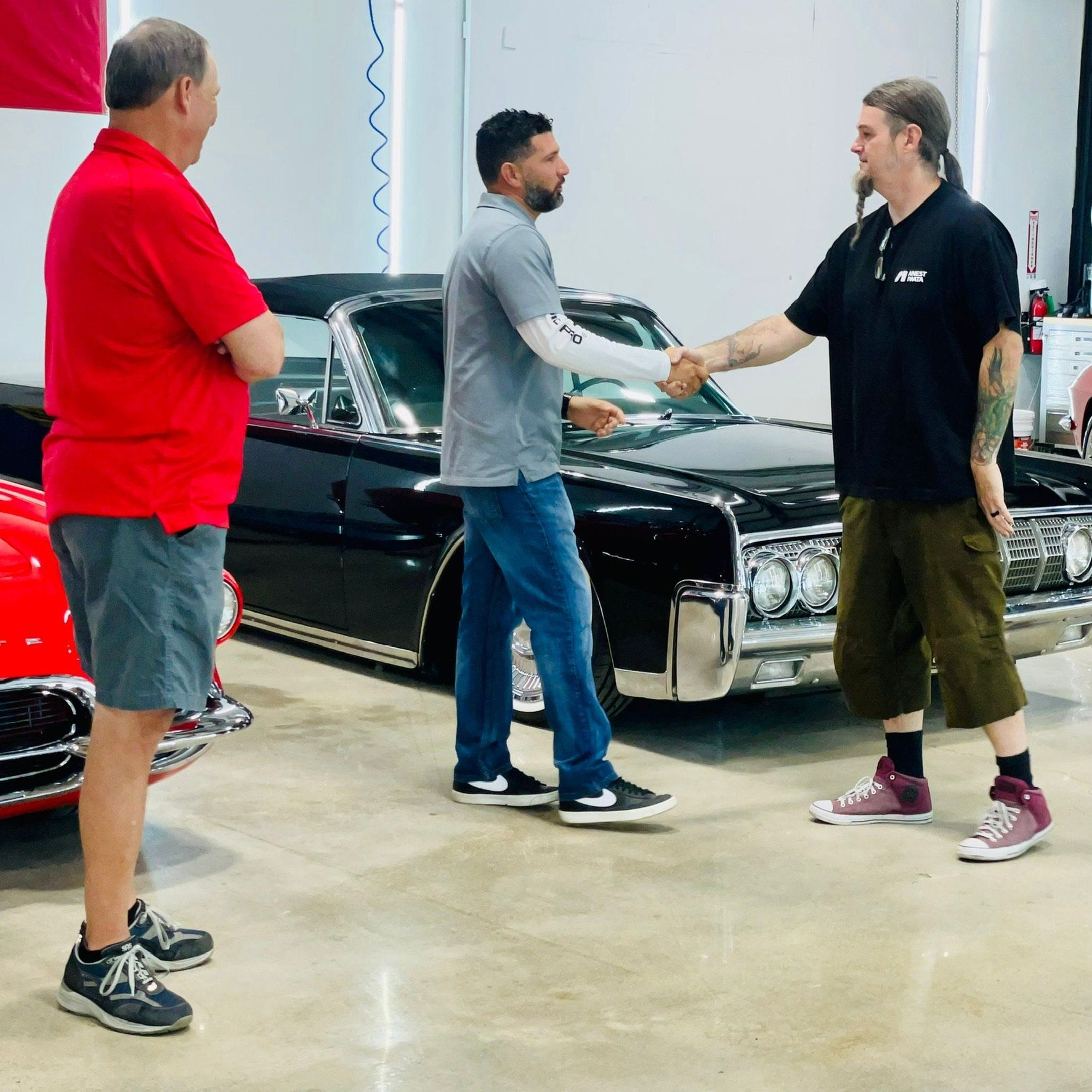 A man in a red shirt shakes hands with a man in a black shirt