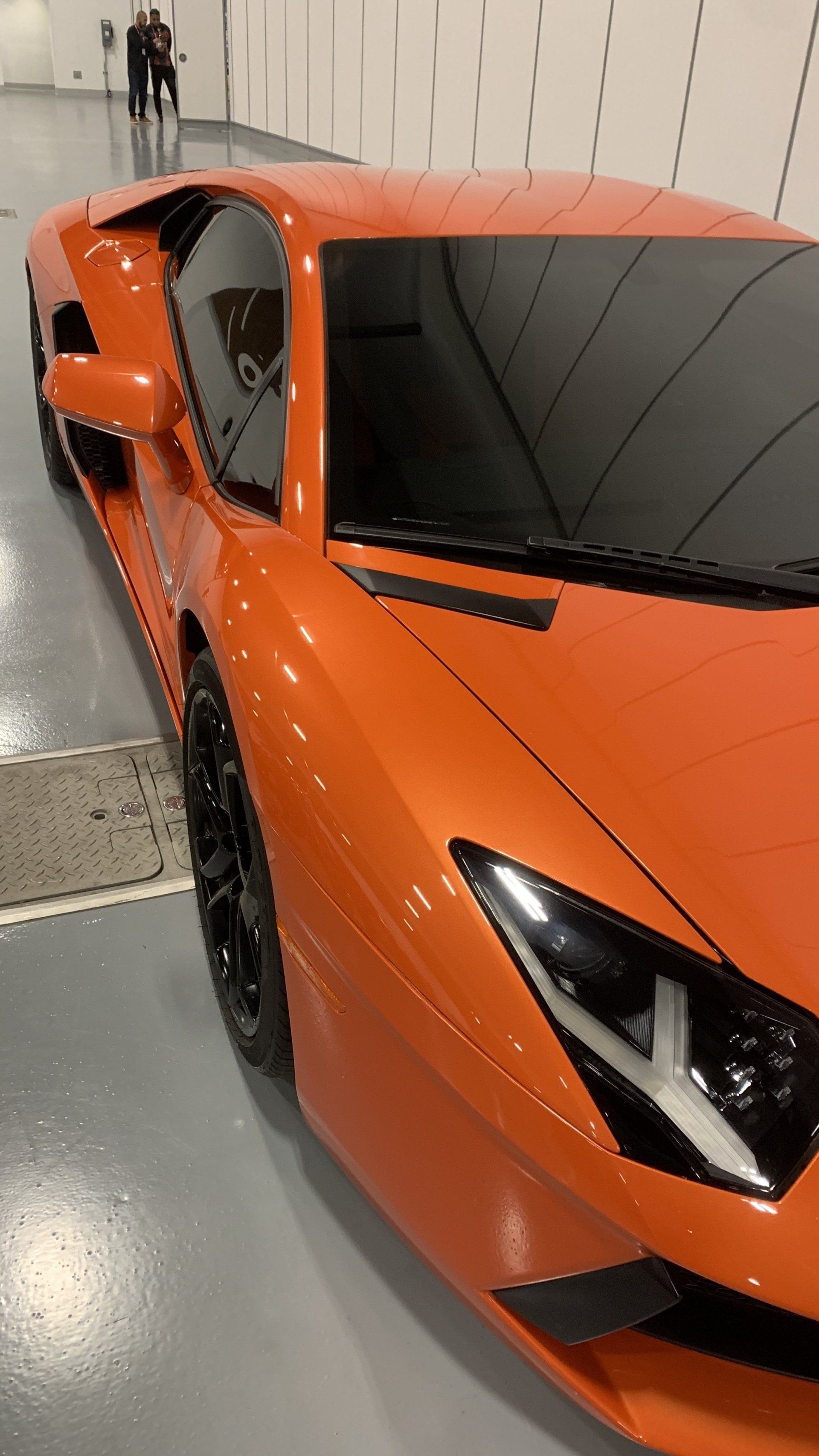 An orange sports car is parked in a garage
