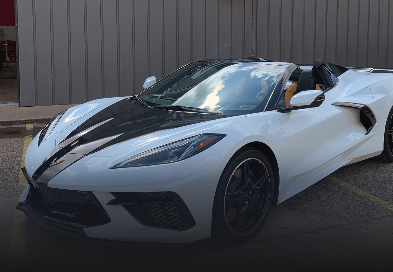 A white corvette convertible is parked in front of a building.