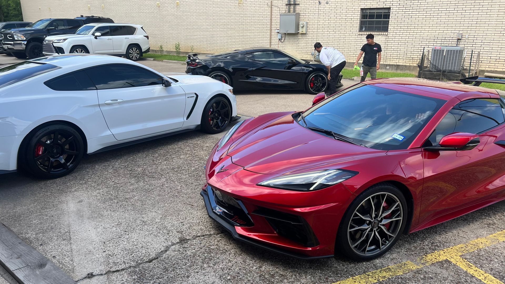 A white mustang and a red corvette are parked next to each other in a parking lot.