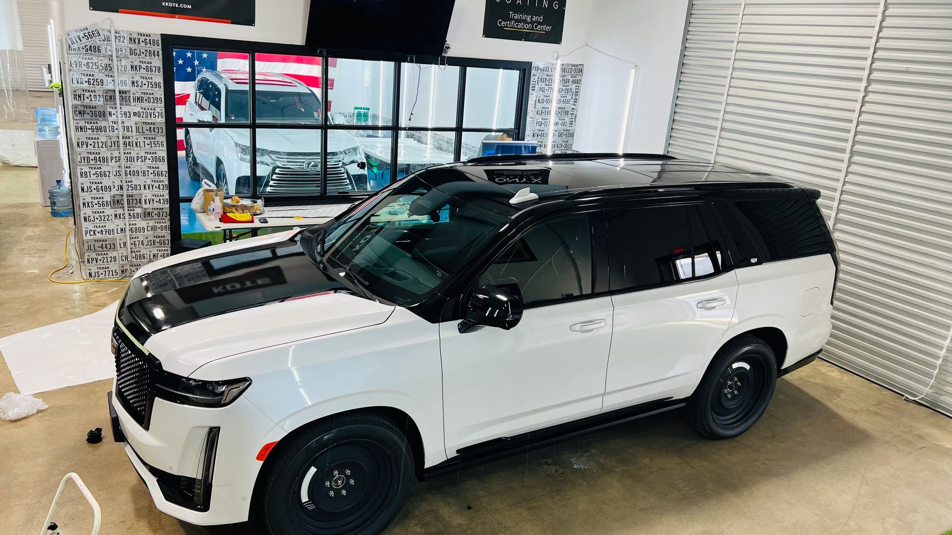 A white suv is parked in a garage next to a wall.