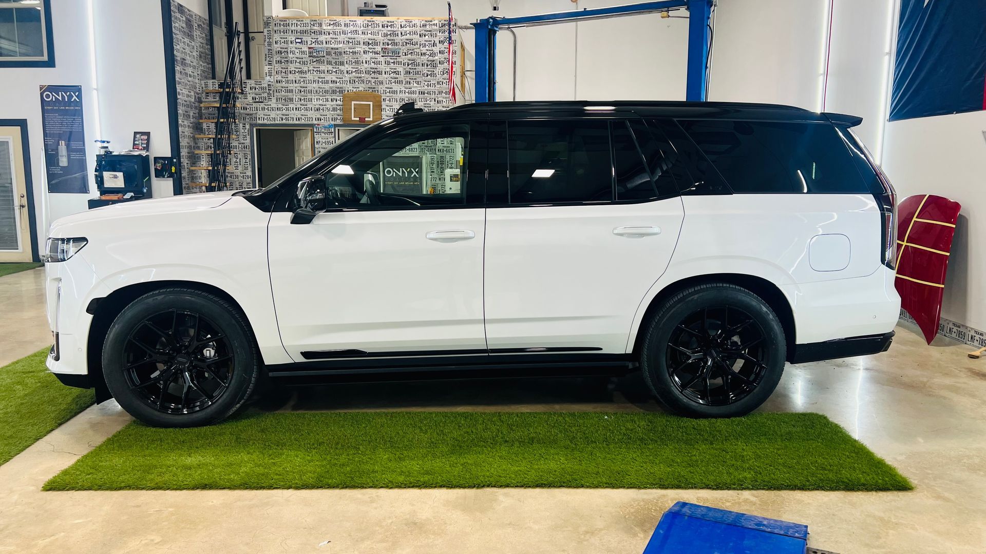 A white suv is parked on a green mat in a garage.