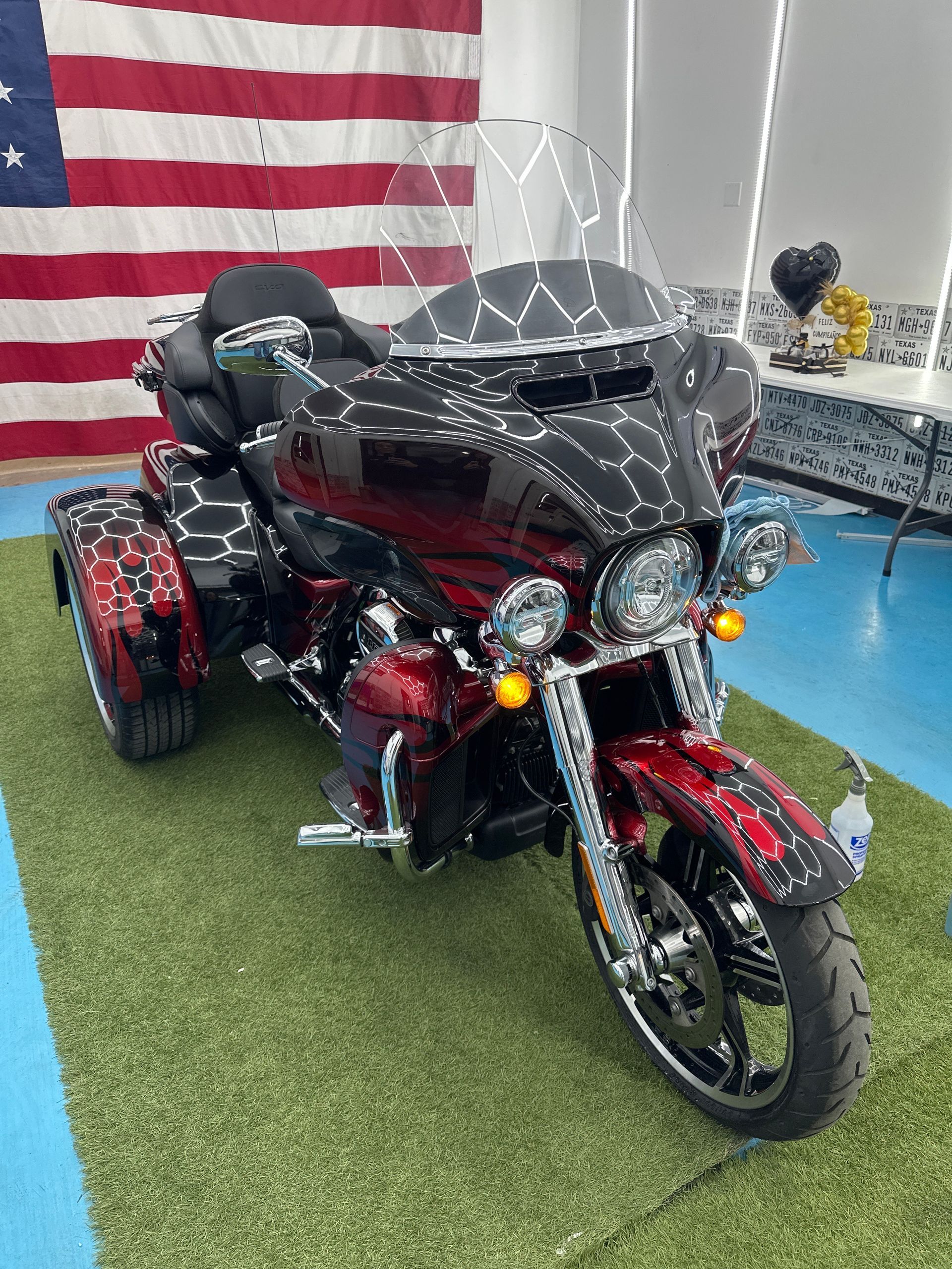 A red and black motorcycle is parked on the grass in front of an american flag.