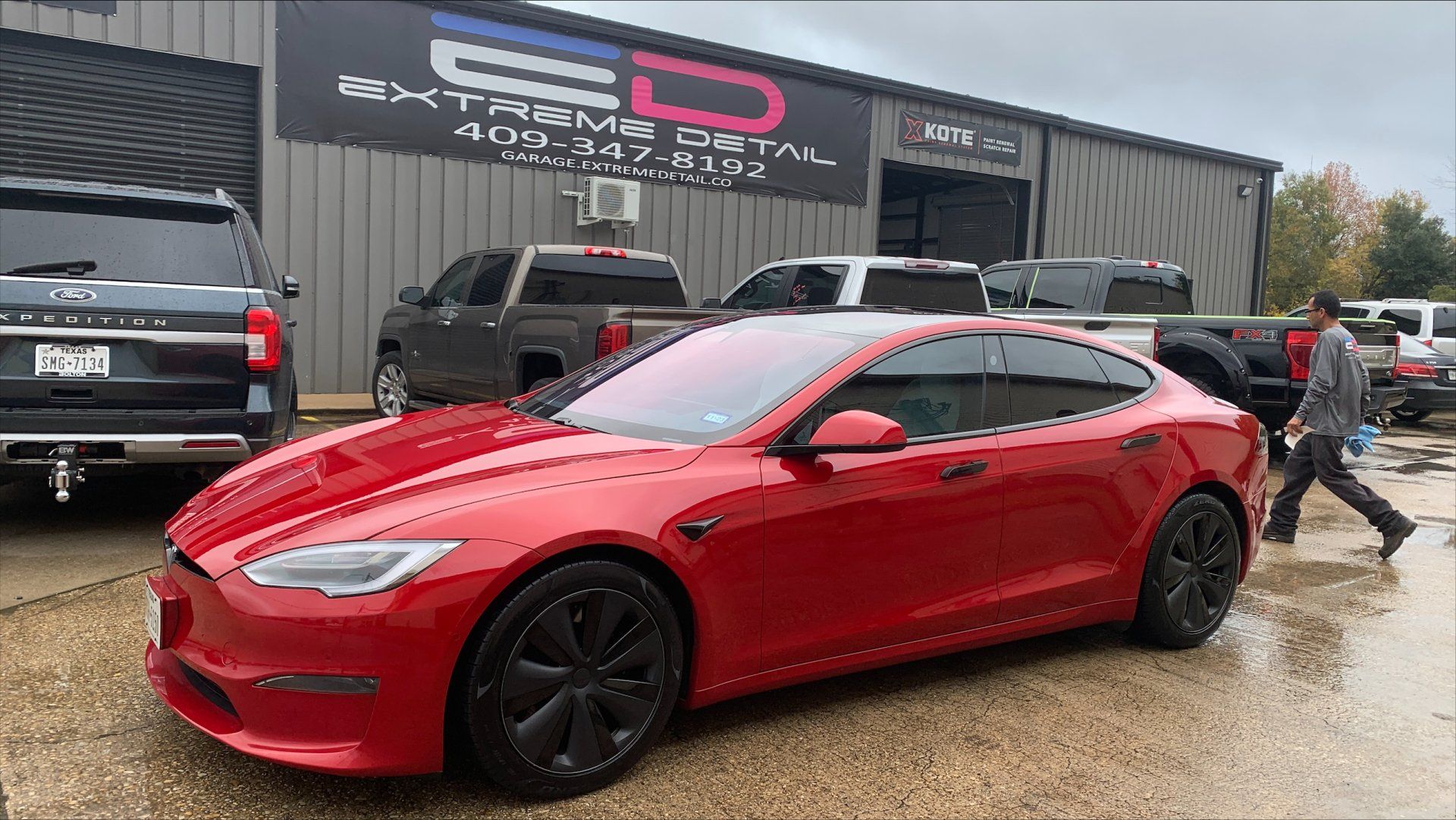 A red tesla model s is parked in front of a building.