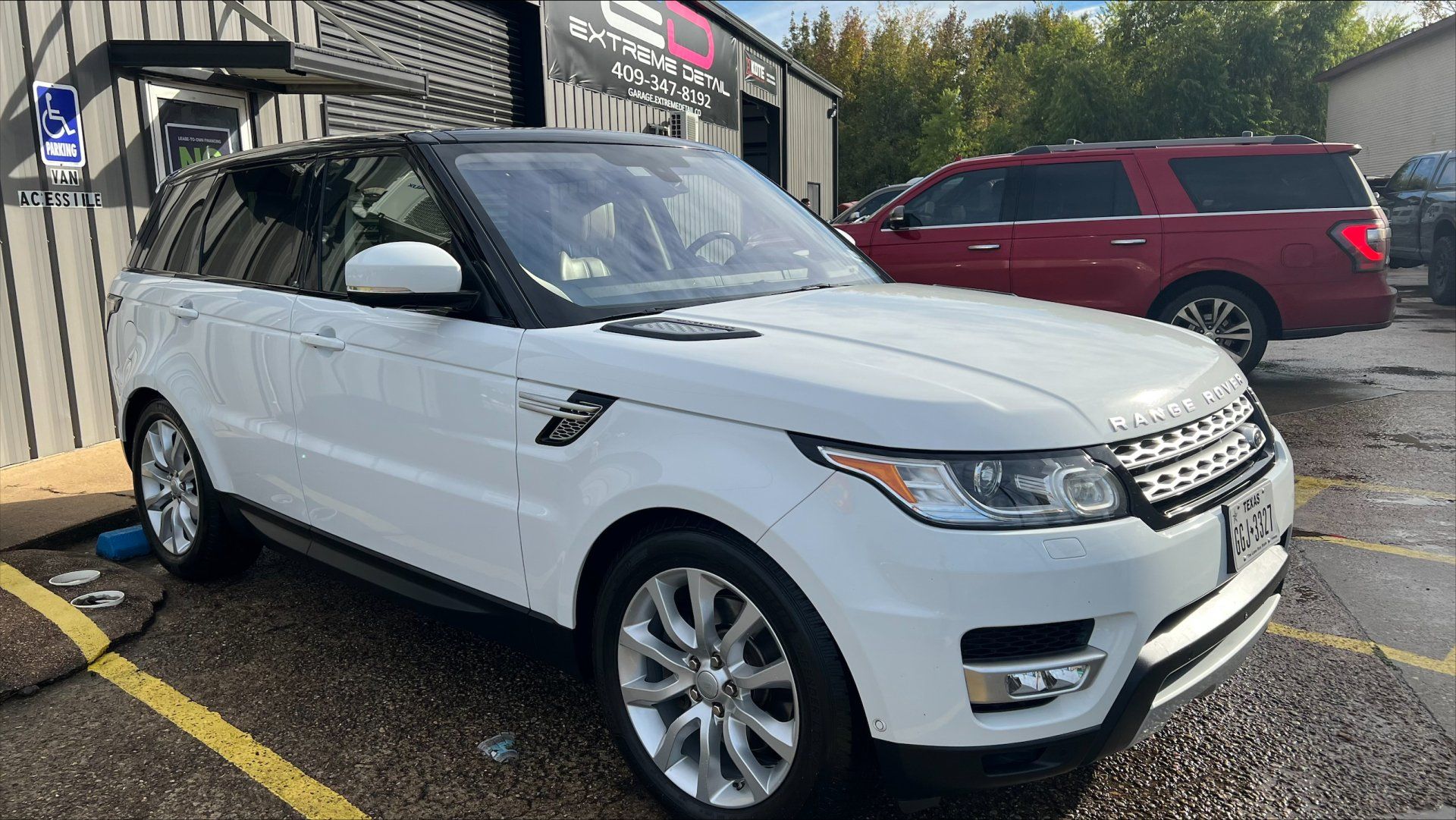 A white range rover sport is parked in a handicapped parking spot.