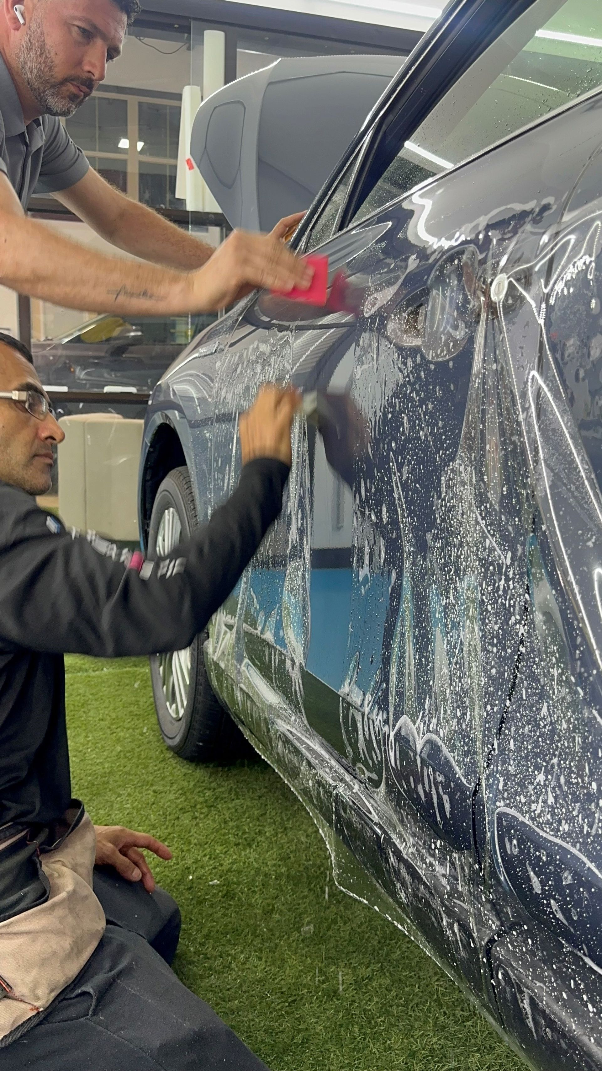 Two men are cleaning a car with a brush.