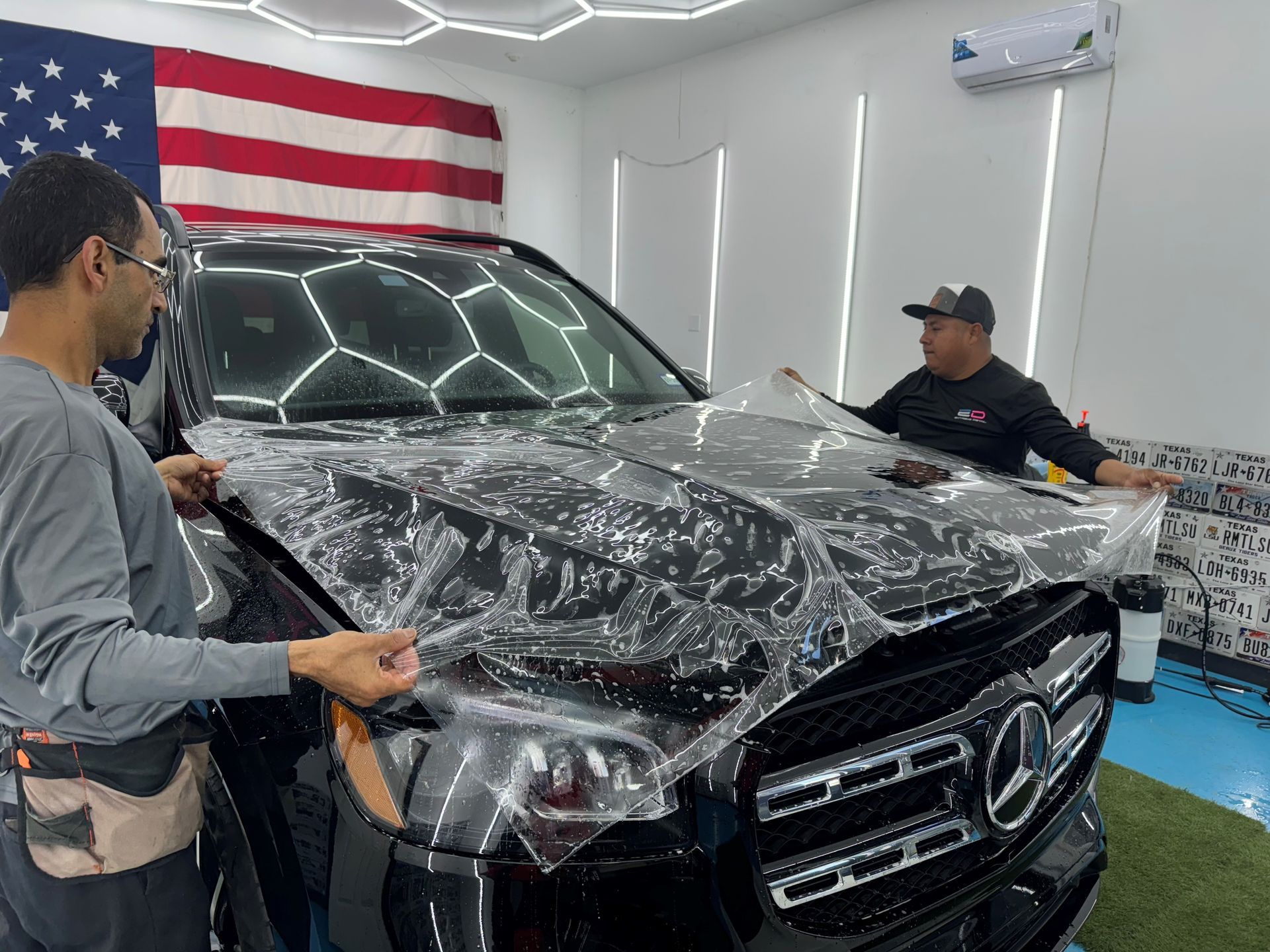 A man is wrapping the hood of a car.