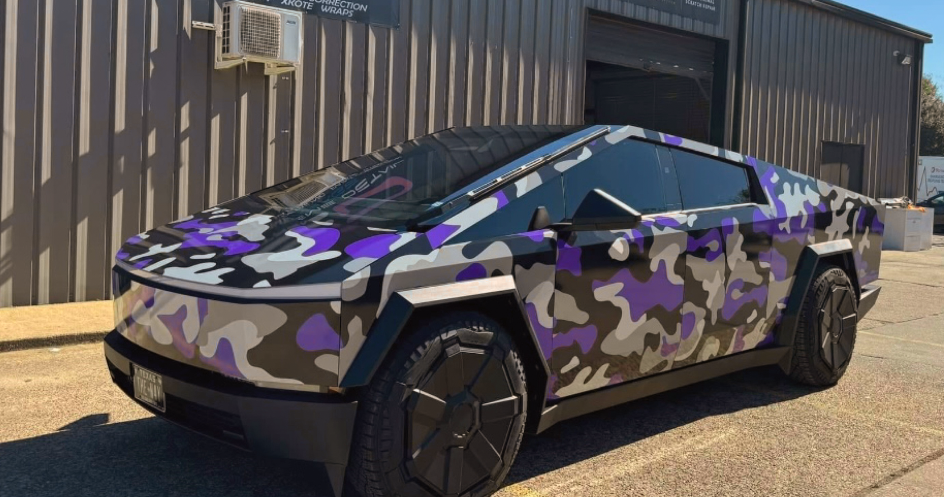 A purple camouflage car is parked in front of a building.