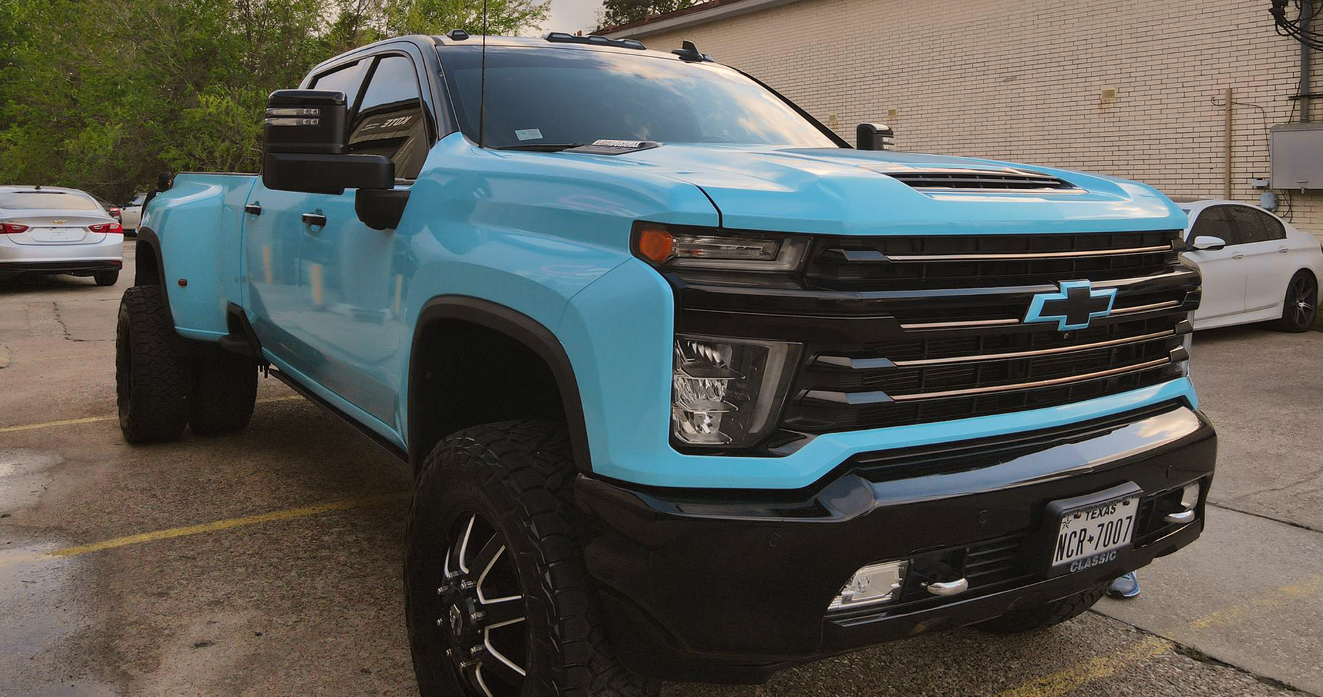 A blue truck is parked in a parking lot next to a building.