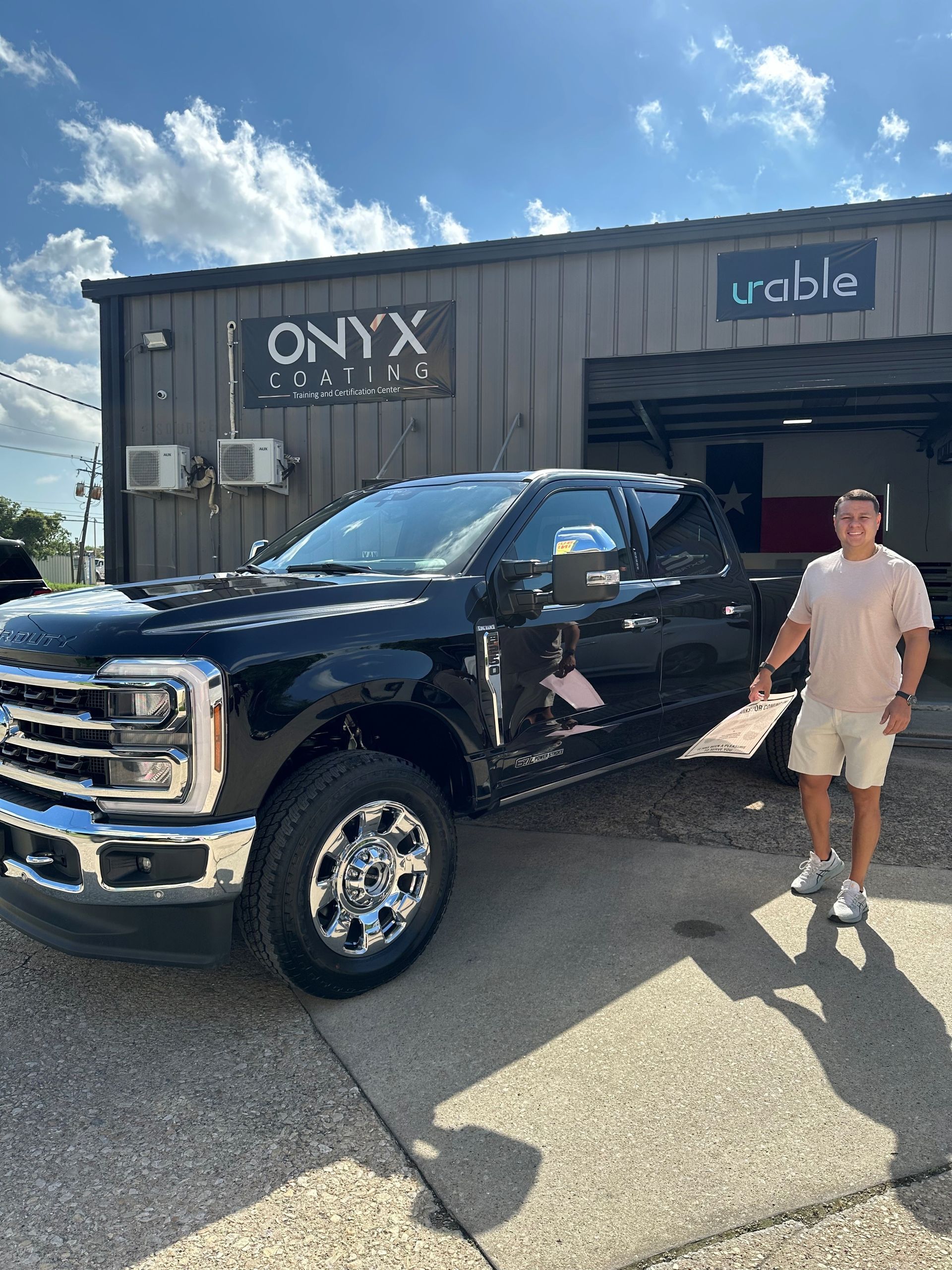 A man is standing on the driver side of a black truck.