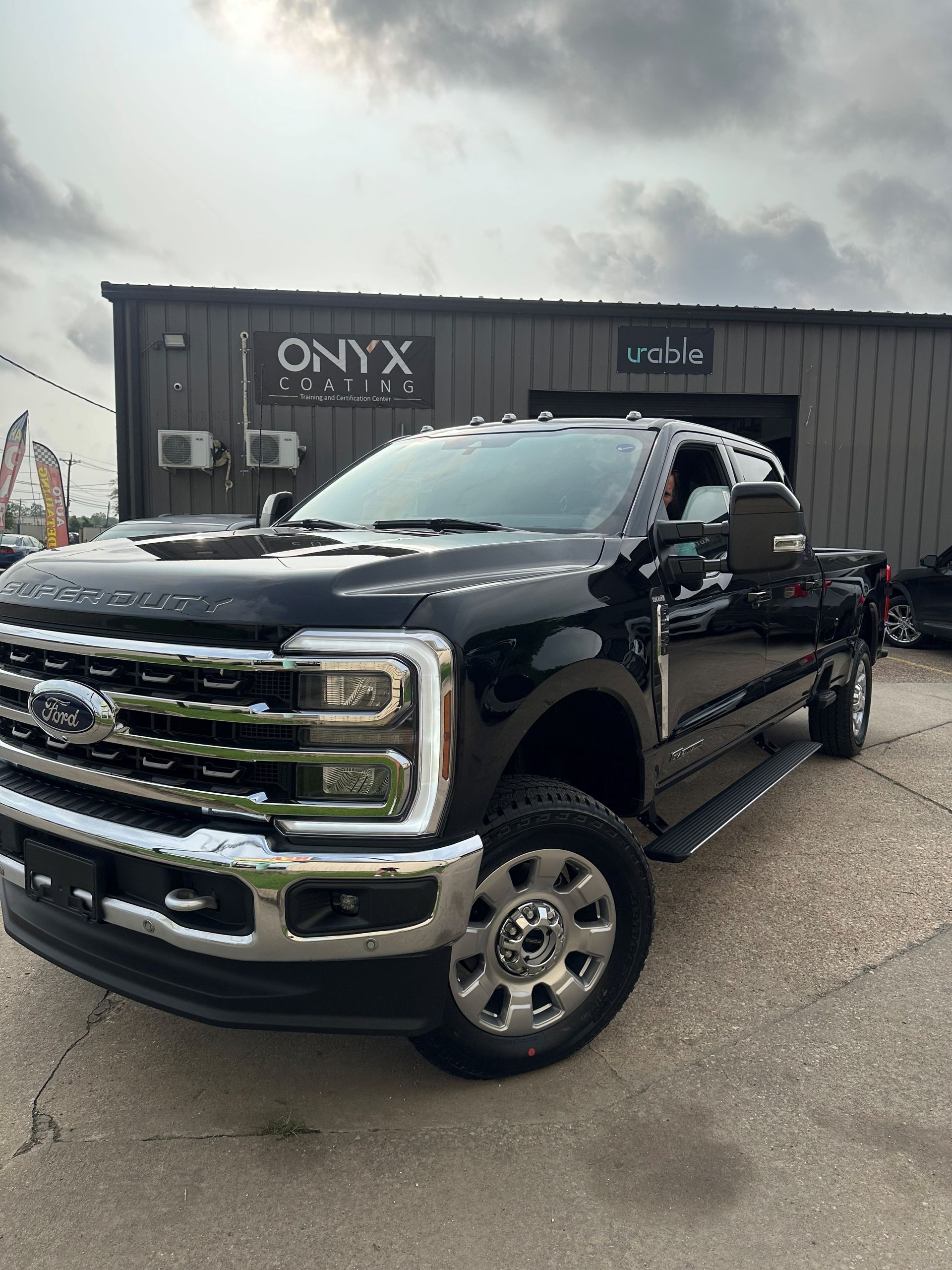 A black ford truck is parked in front of a building.
