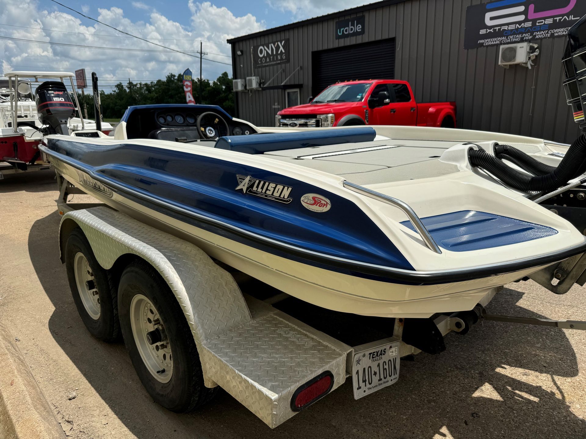 A blue and white boat is parked on a trailer in front of a building.