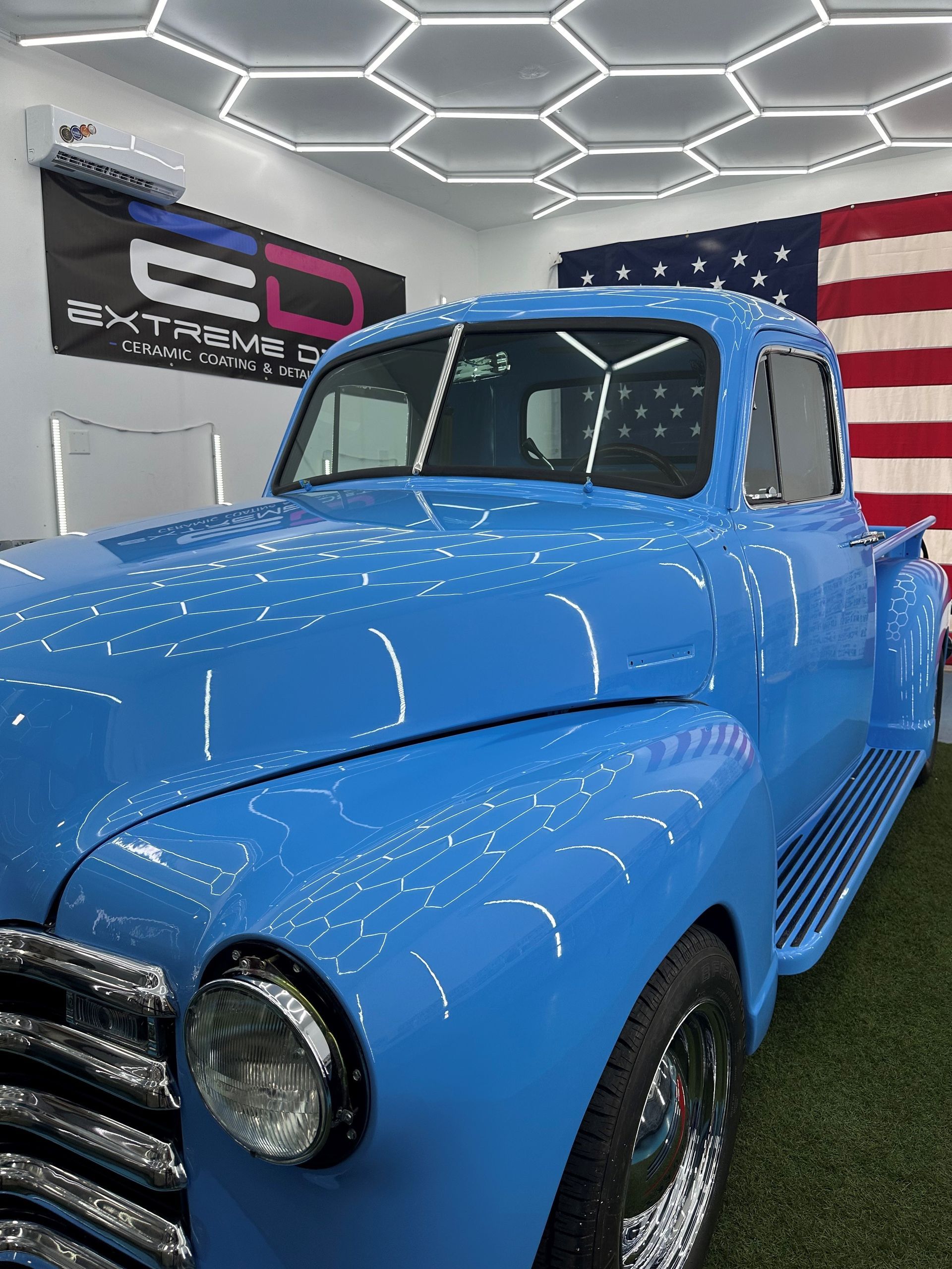 A blue truck is parked in a car detailing garage