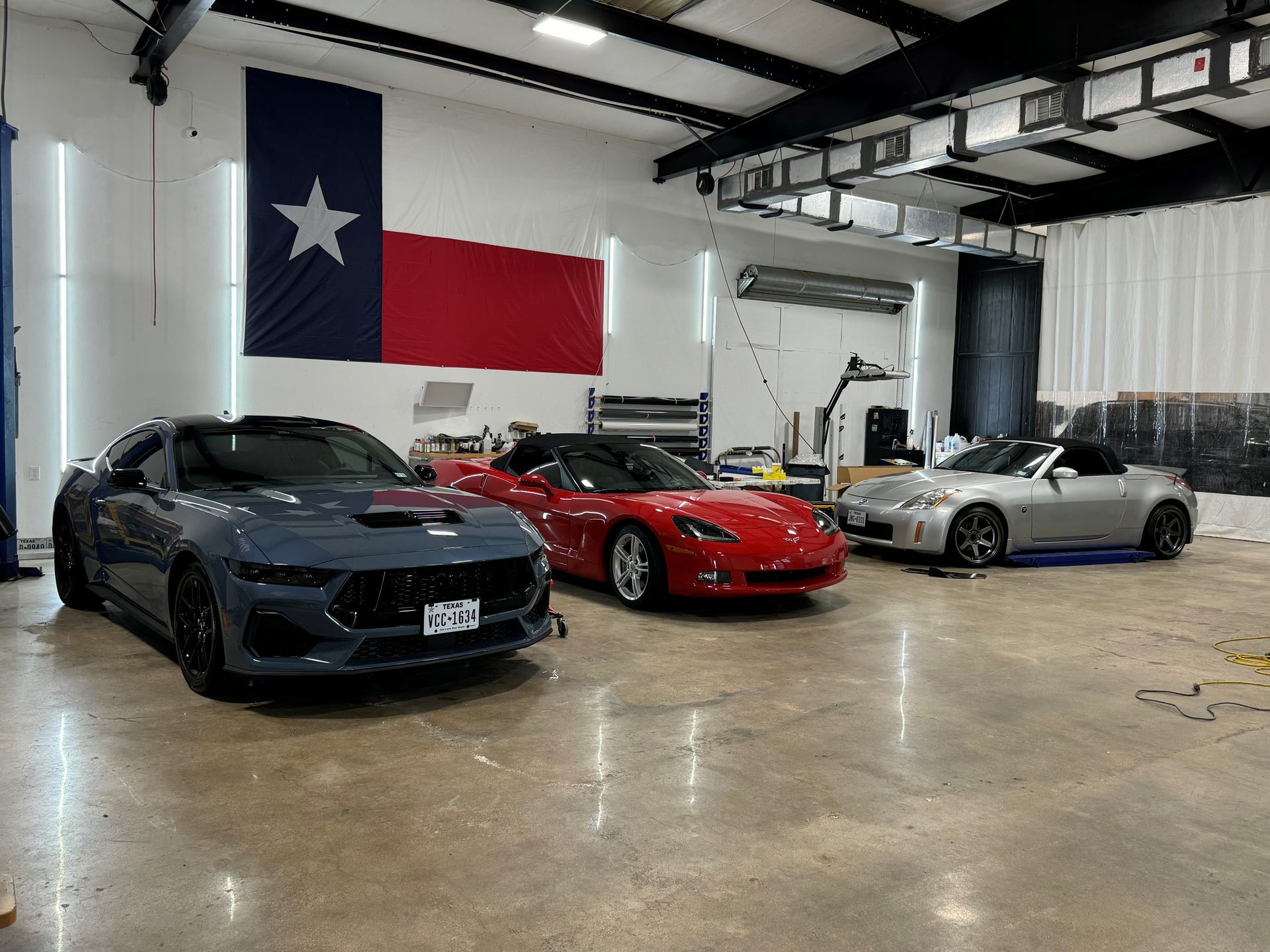 Three cars are parked in a car detailing garage.