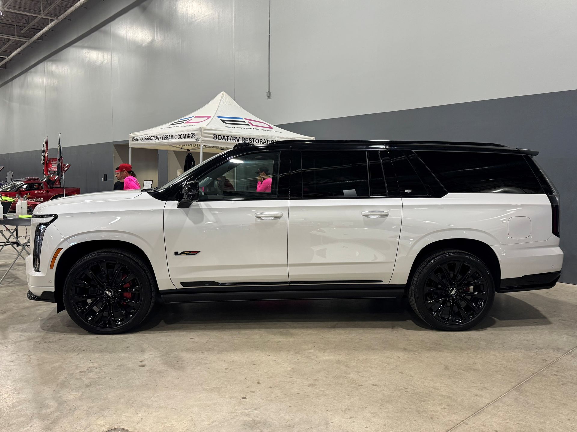 A white suv is parked in a garage next to a tent.