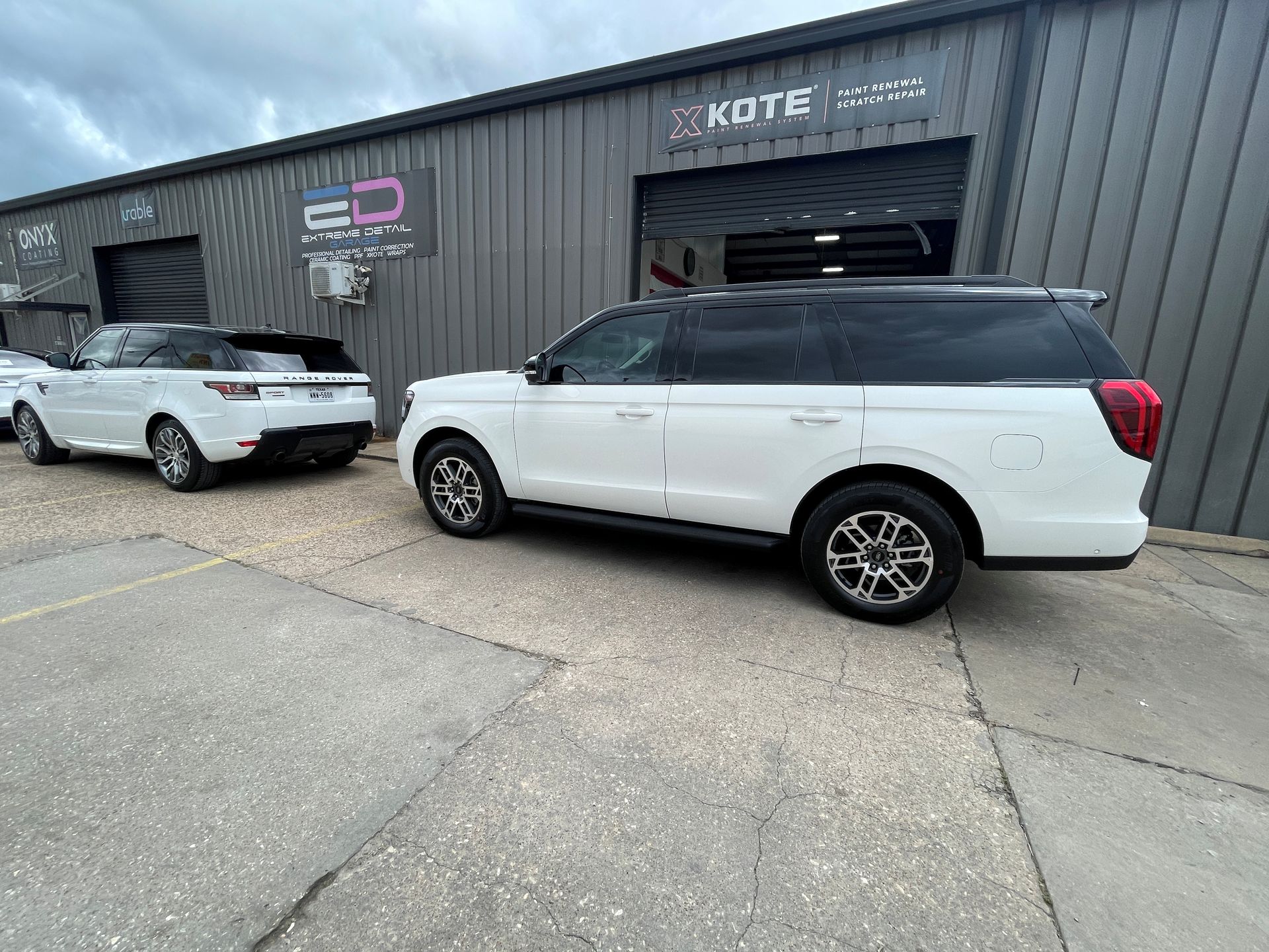 Two white suvs are parked in front of a building.