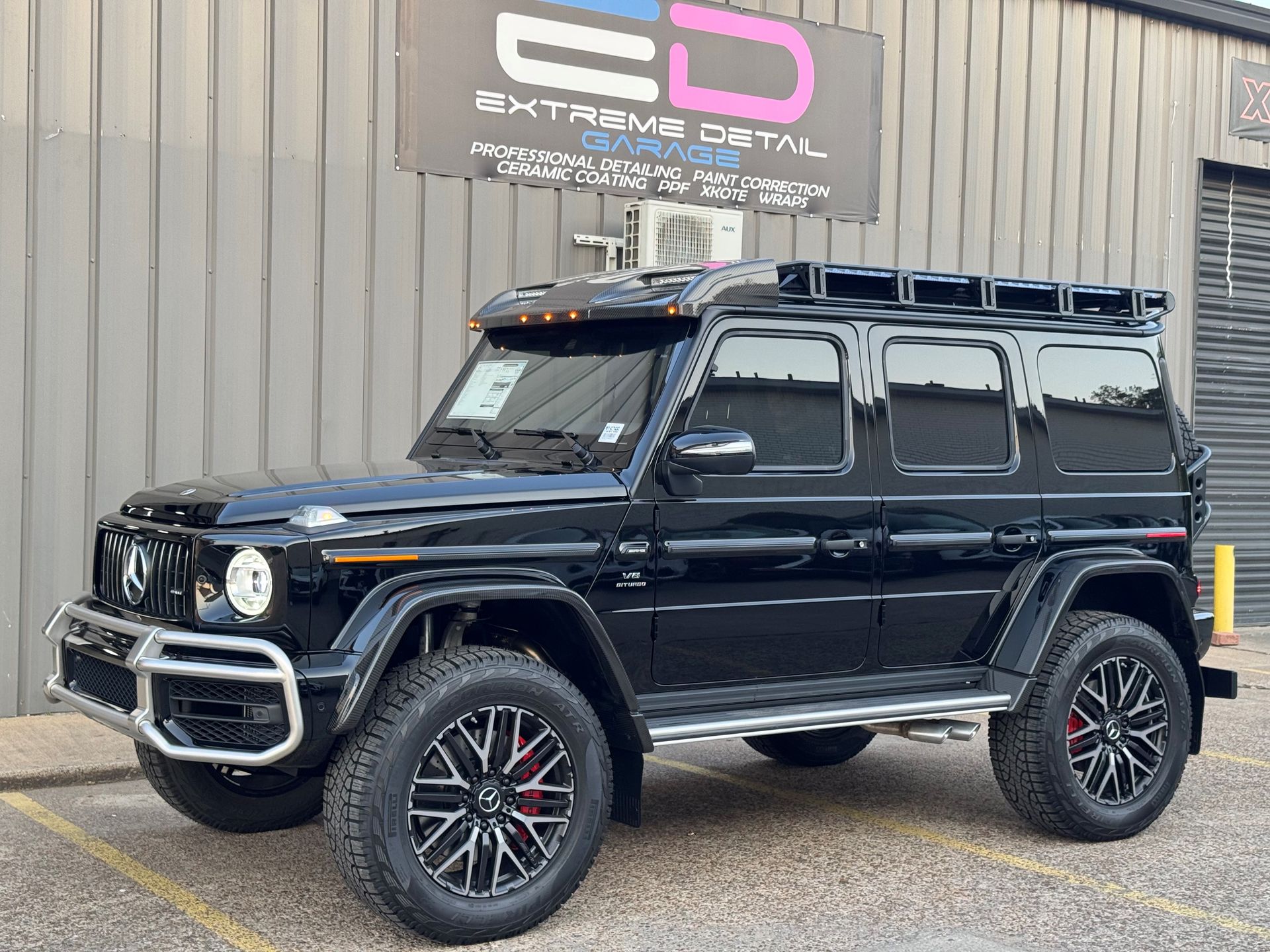 A black mercedes benz g63 amg is parked in front of a building.