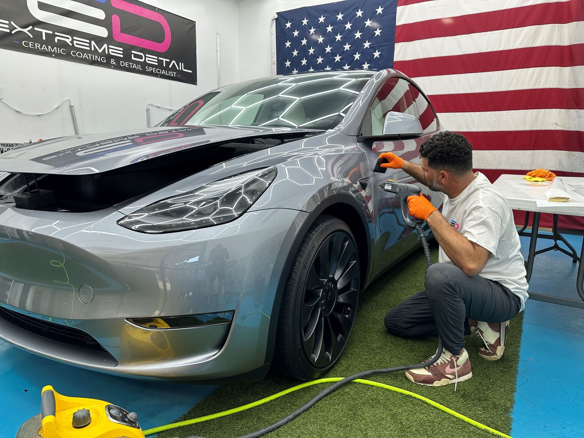 A man is working on a tesla model y in a garage.