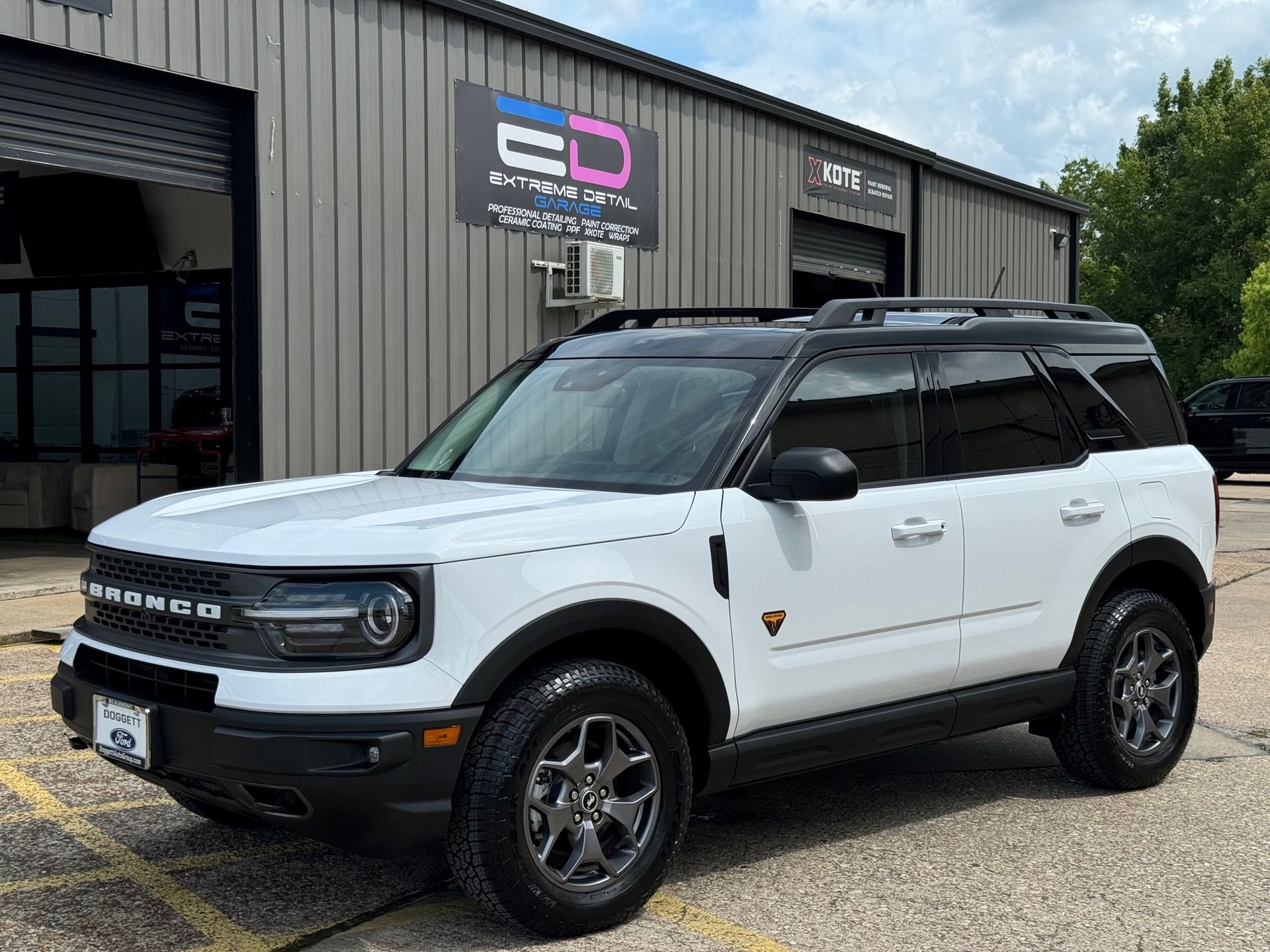 A white ford bronco sport is parked in front of a building.
