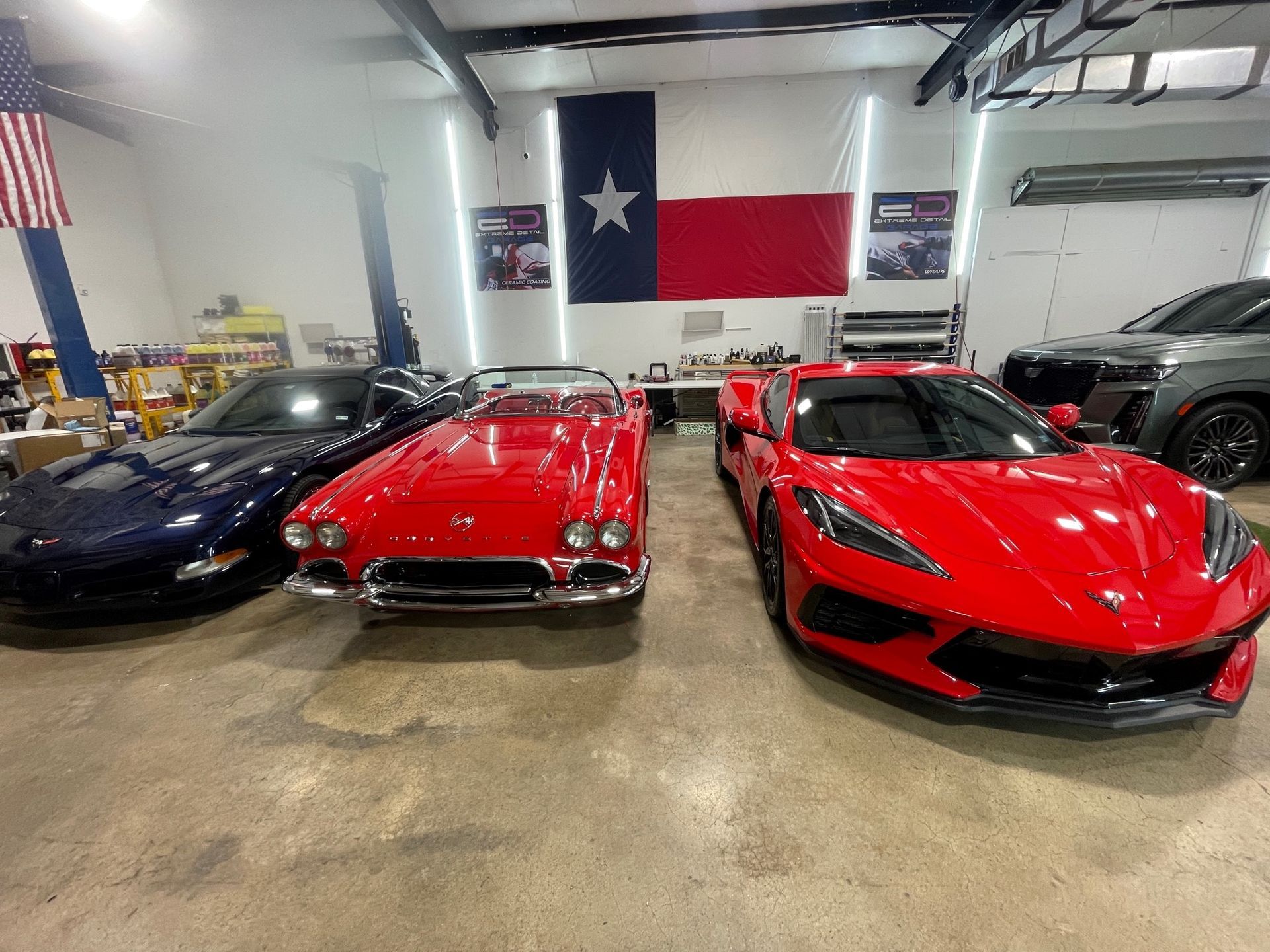 A group of cars are parked in a garage with a texas flag in the background.
