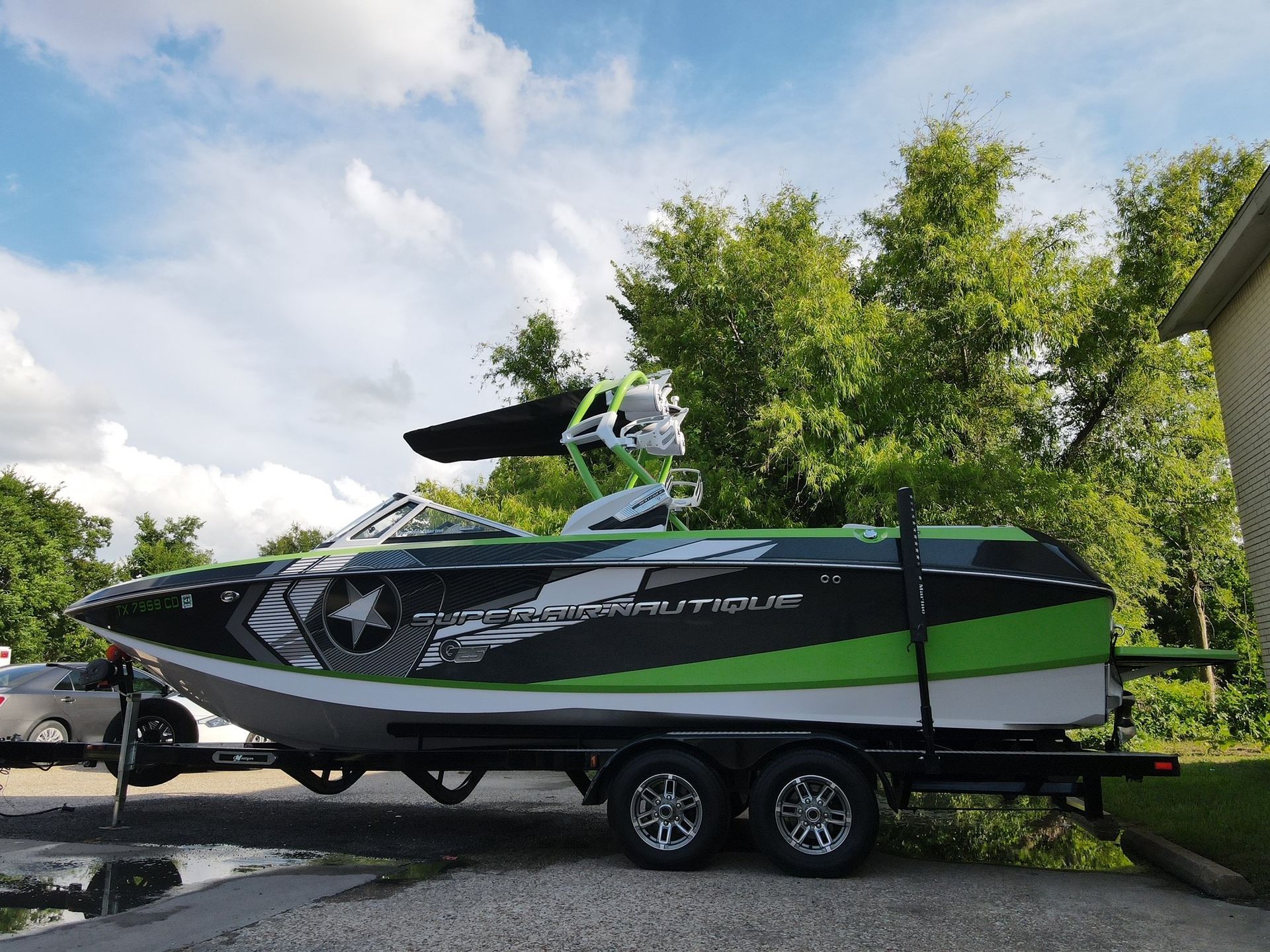 A green and black boat is parked on a trailer