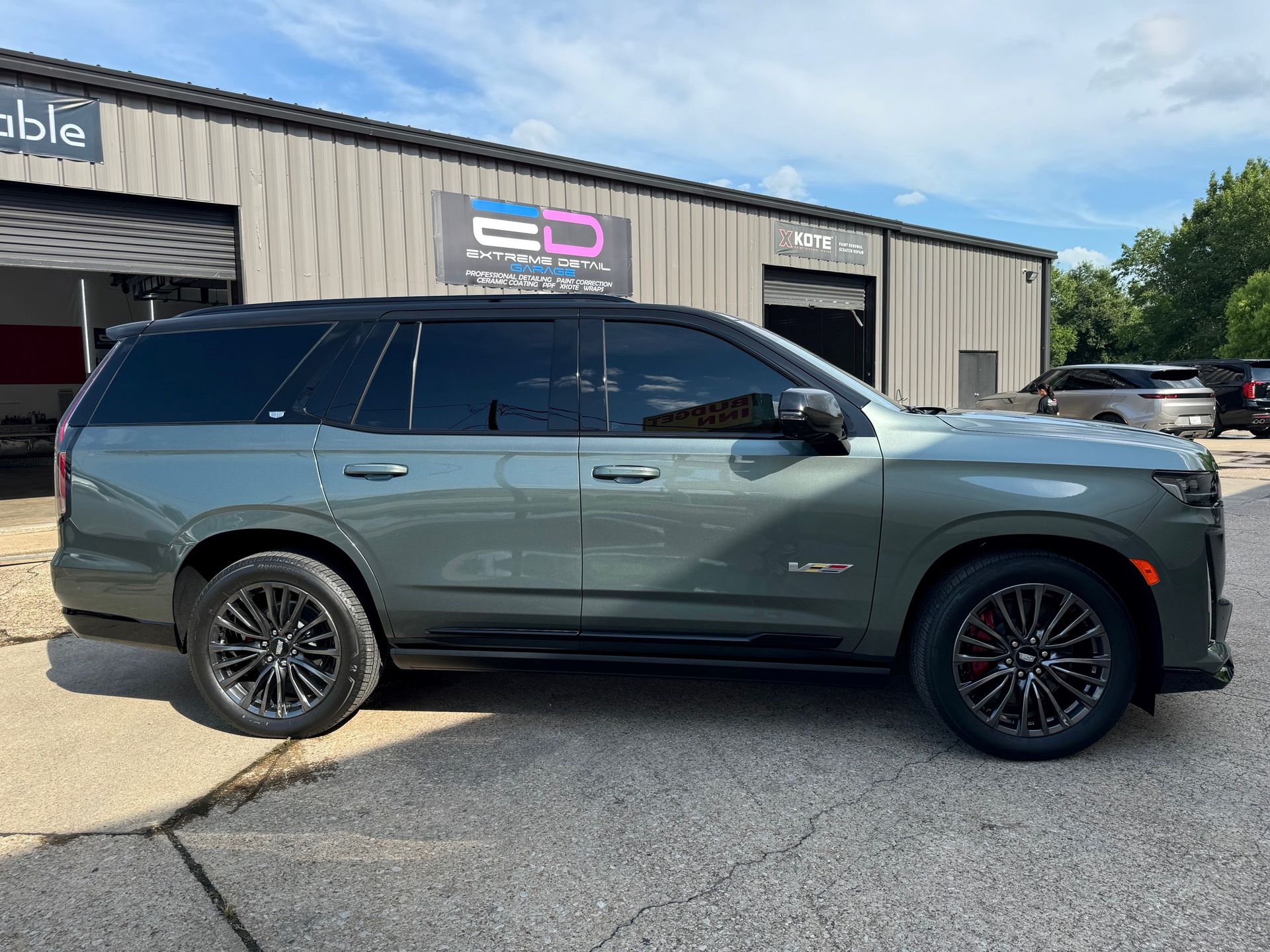 A green suv is parked in front of a building.