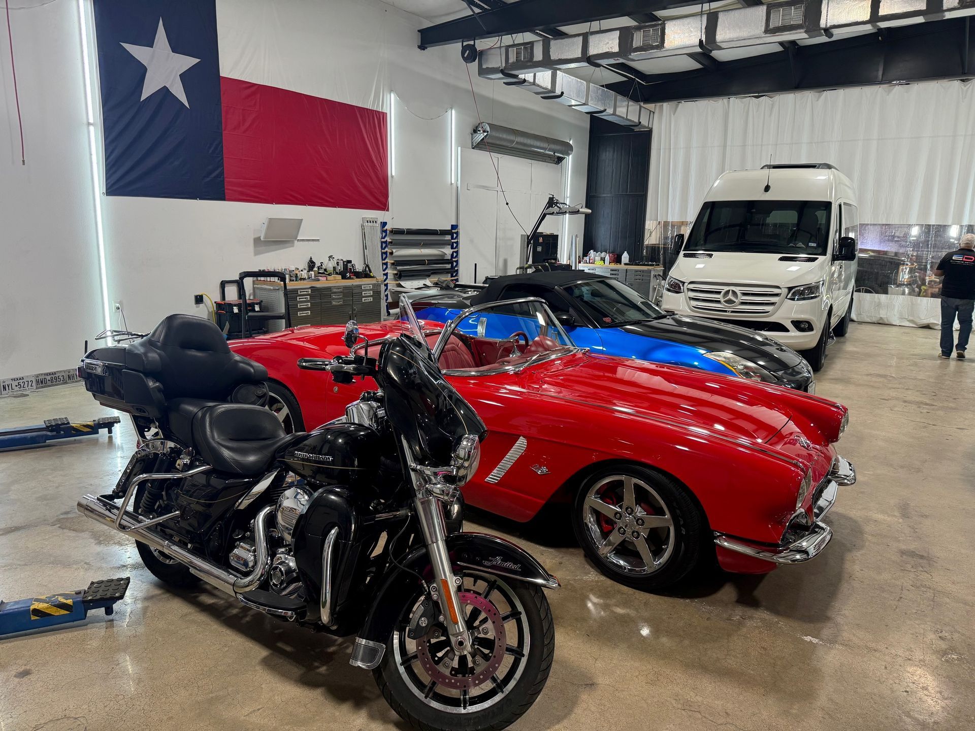 A motorcycle is parked next to a red car in a garage.