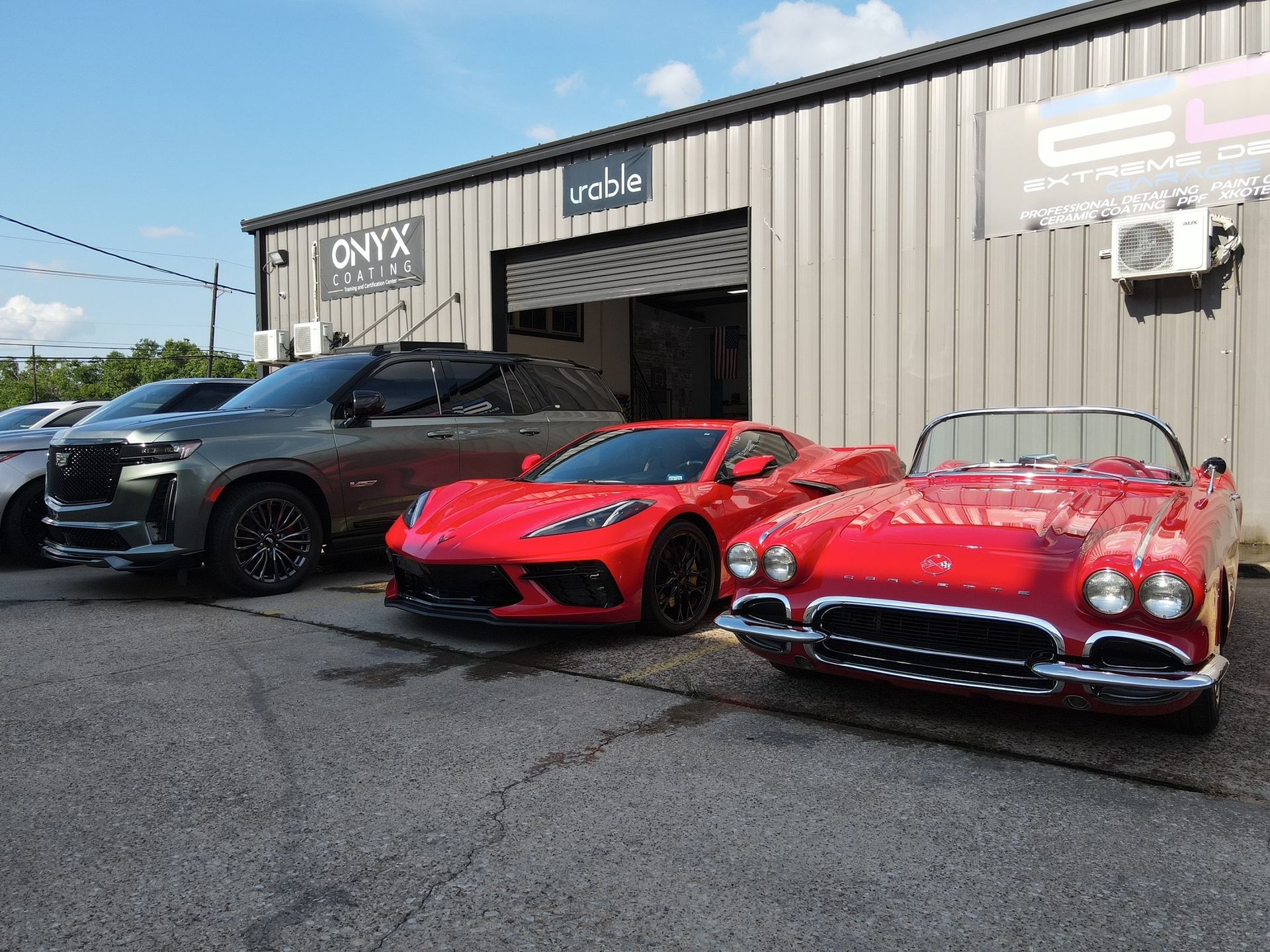 Three red cars are parked in front of a building.