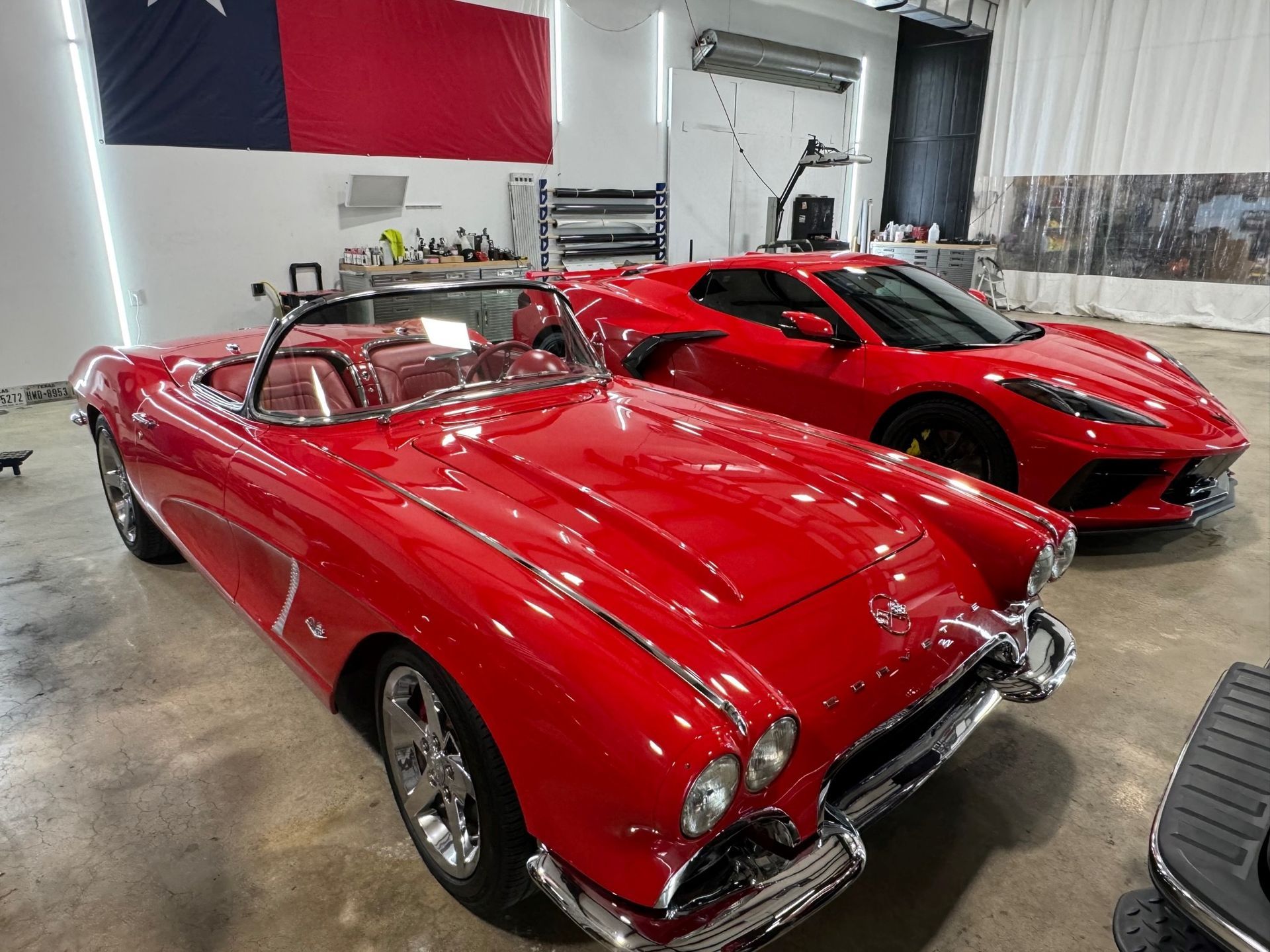 Two red sports cars are parked next to each other in a garage.