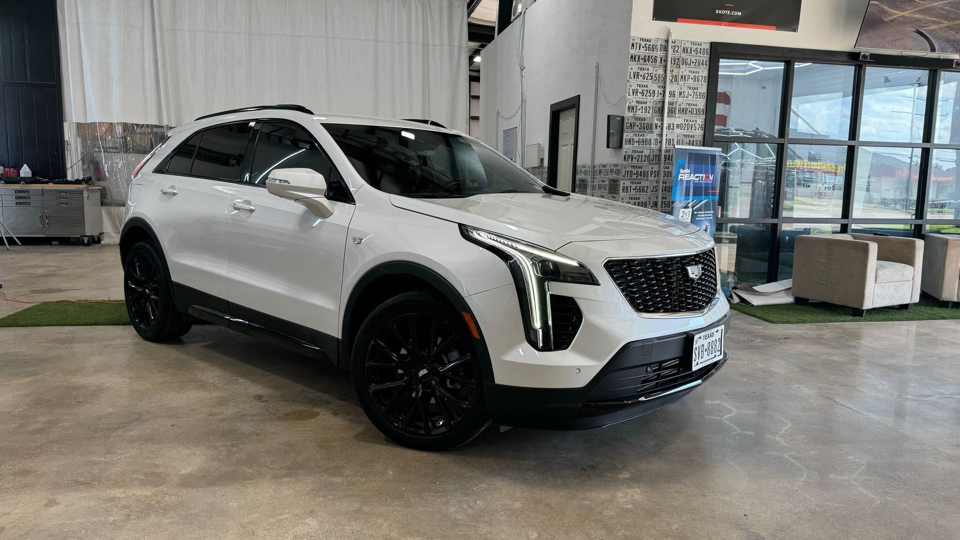 A white cadillac xt4 is parked in a showroom.