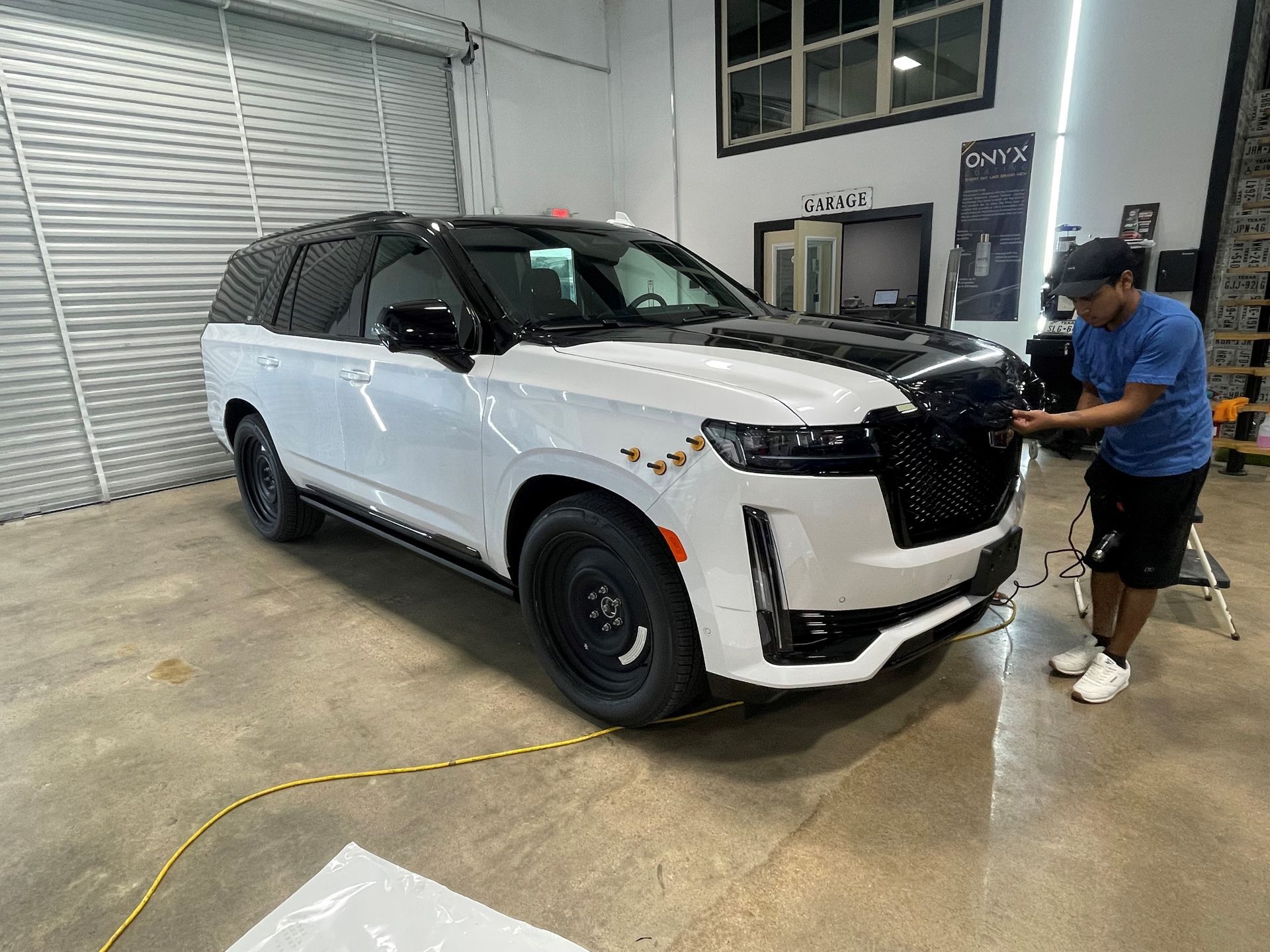 A man is working on a white suv in a garage.