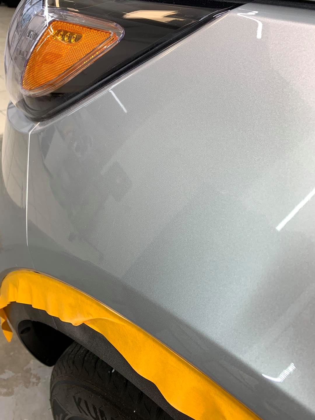 A close up of a car 's fender with yellow tape on it.