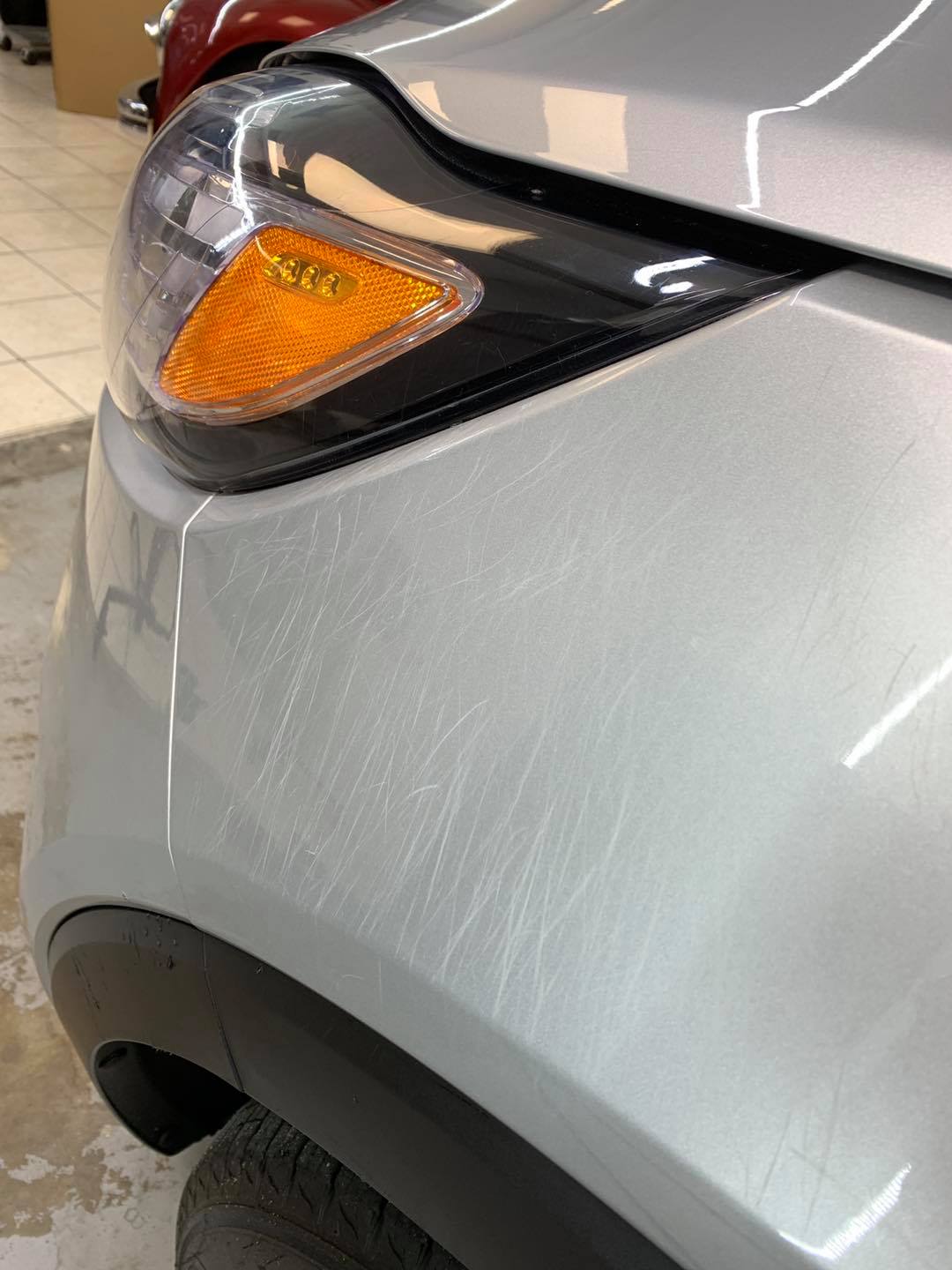 A close up of a silver car 's headlight in a garage.