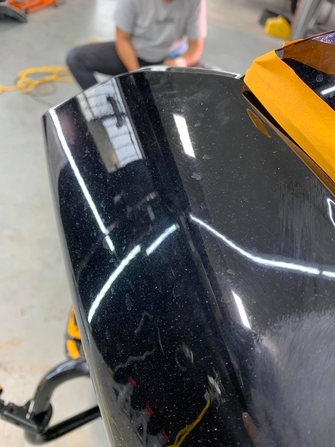 A close up of a black car with yellow tape on it