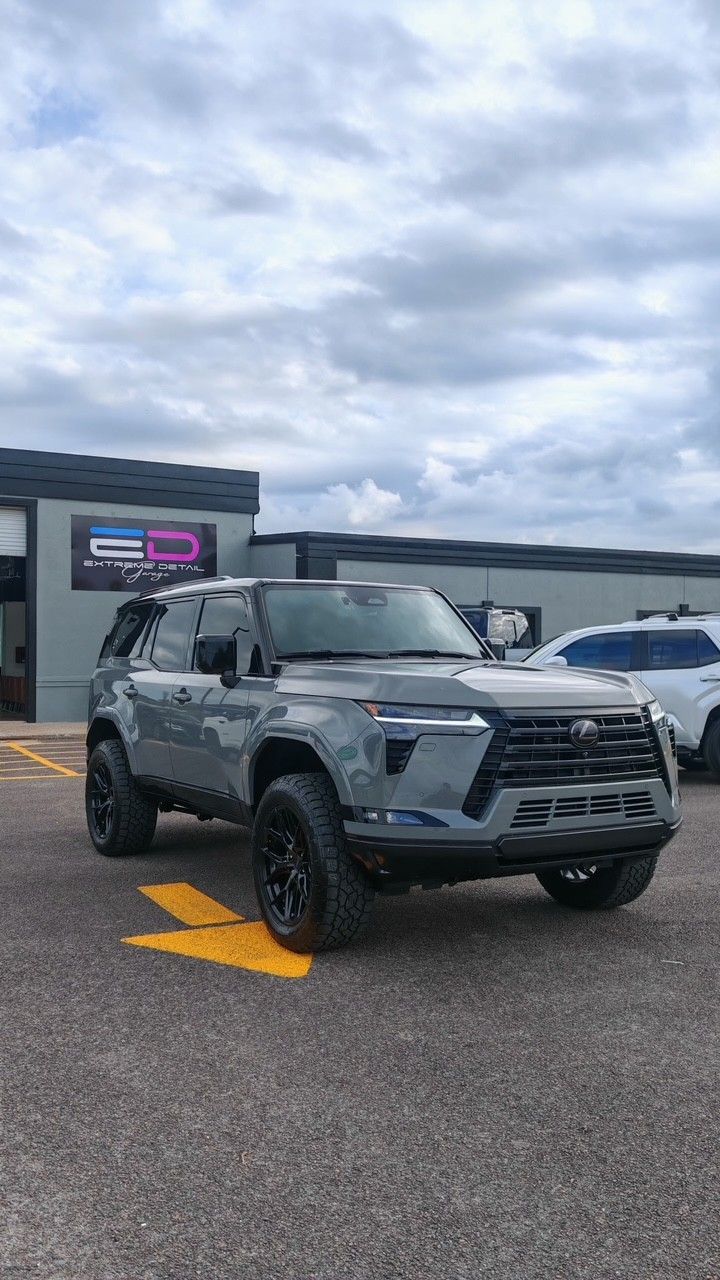 Dark gray SUV parked on a lot under a cloudy sky, with a dealership building in the background