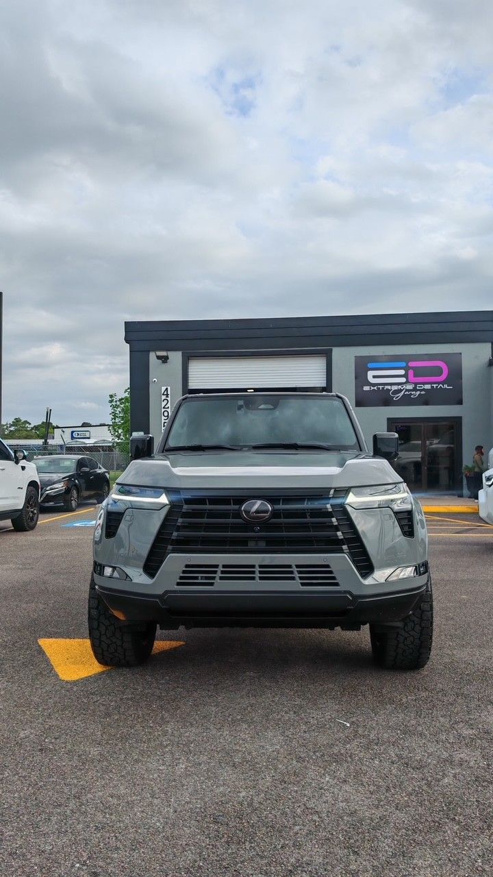 Gray pickup truck parked in front of a storefront on a cloudy day.
