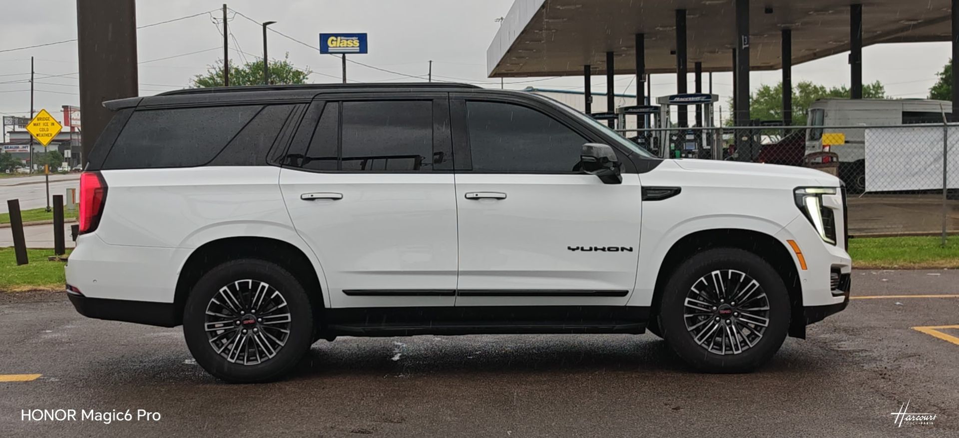 White SUV parked in profile on a wet street under an overcast sky