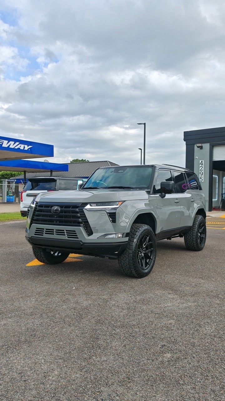 Gray pickup truck parked outside a dealership under cloudy skies