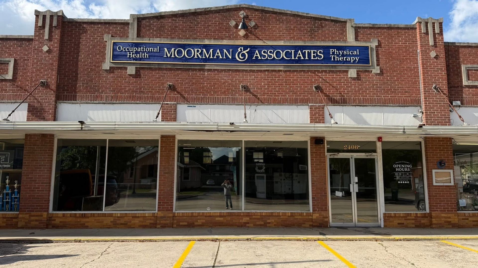 Brick storefront with blue “Moorman & Associates, P.C.” sign and large front windows under white awnings.
